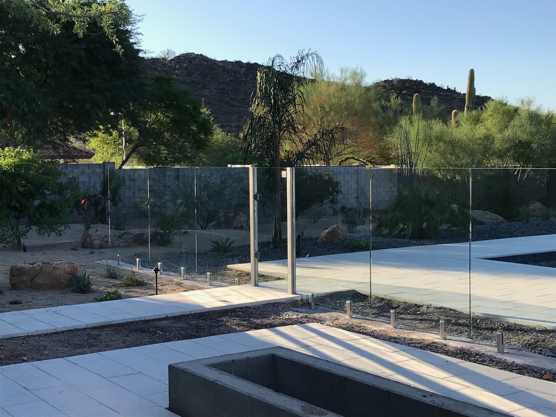 Brushed stainless steel spigots and heavy-duty gate hinges mounted into porcelain paver decking — Arizona glass fencing hardware detail.