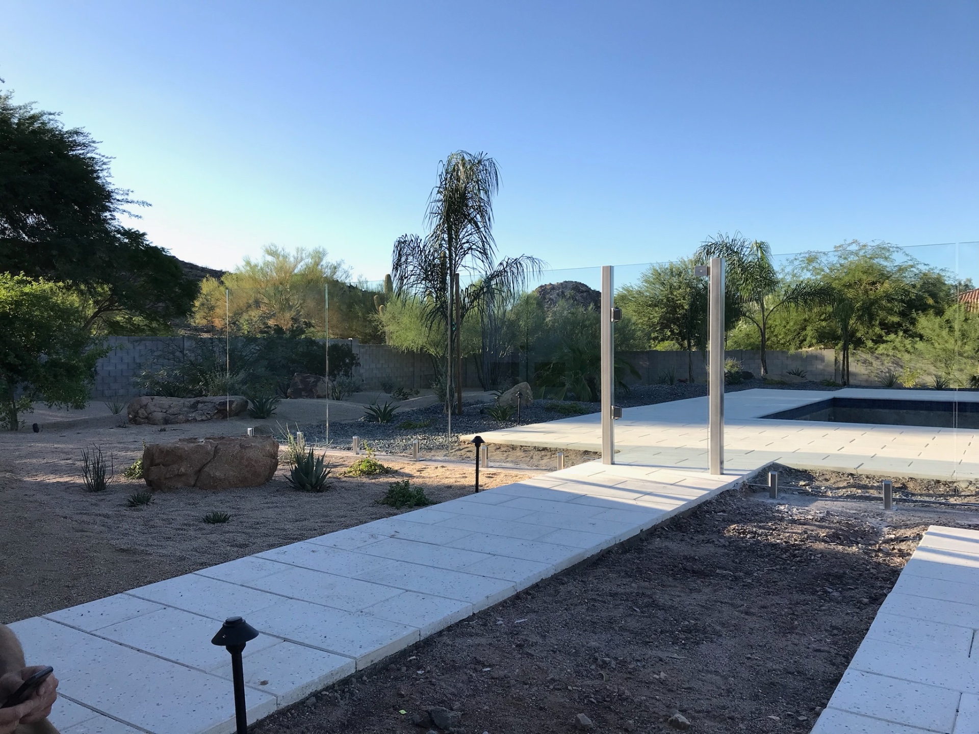 Wide approach pathway leading toward the frameless glass fence gate and desert-integrated pool environment in Scottsdale.