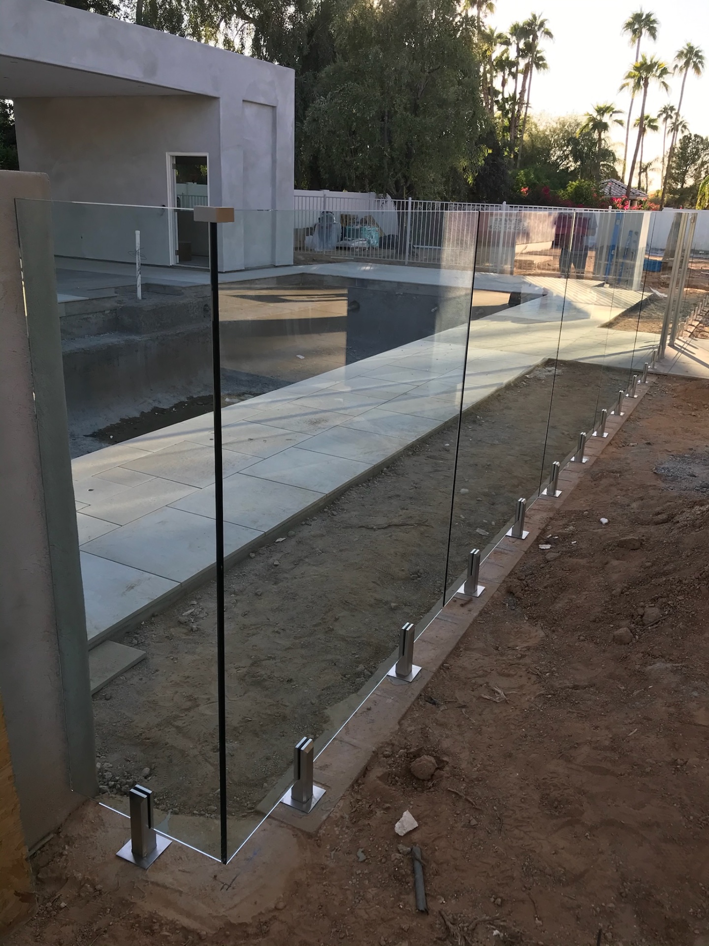 Long run of tempered glass fence panels on stainless spigots along a porcelain paver pool deck during a Phoenix glass fencing install by Sonoran Glass.