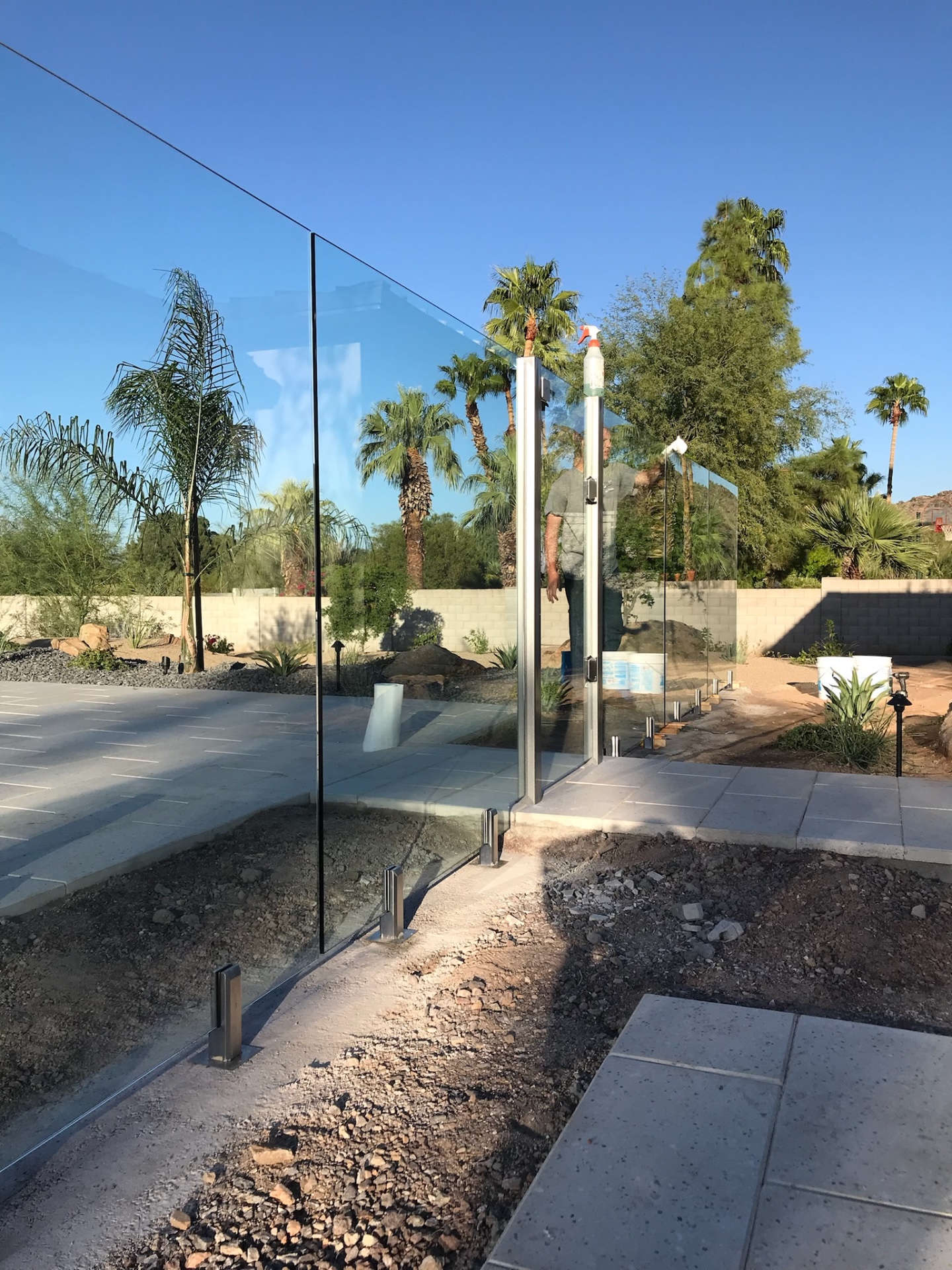 AE craftsman detailing and squeegeeing a frameless glass fence gate panel during final cleanup and handoff on an Arizona glass fencing project.
