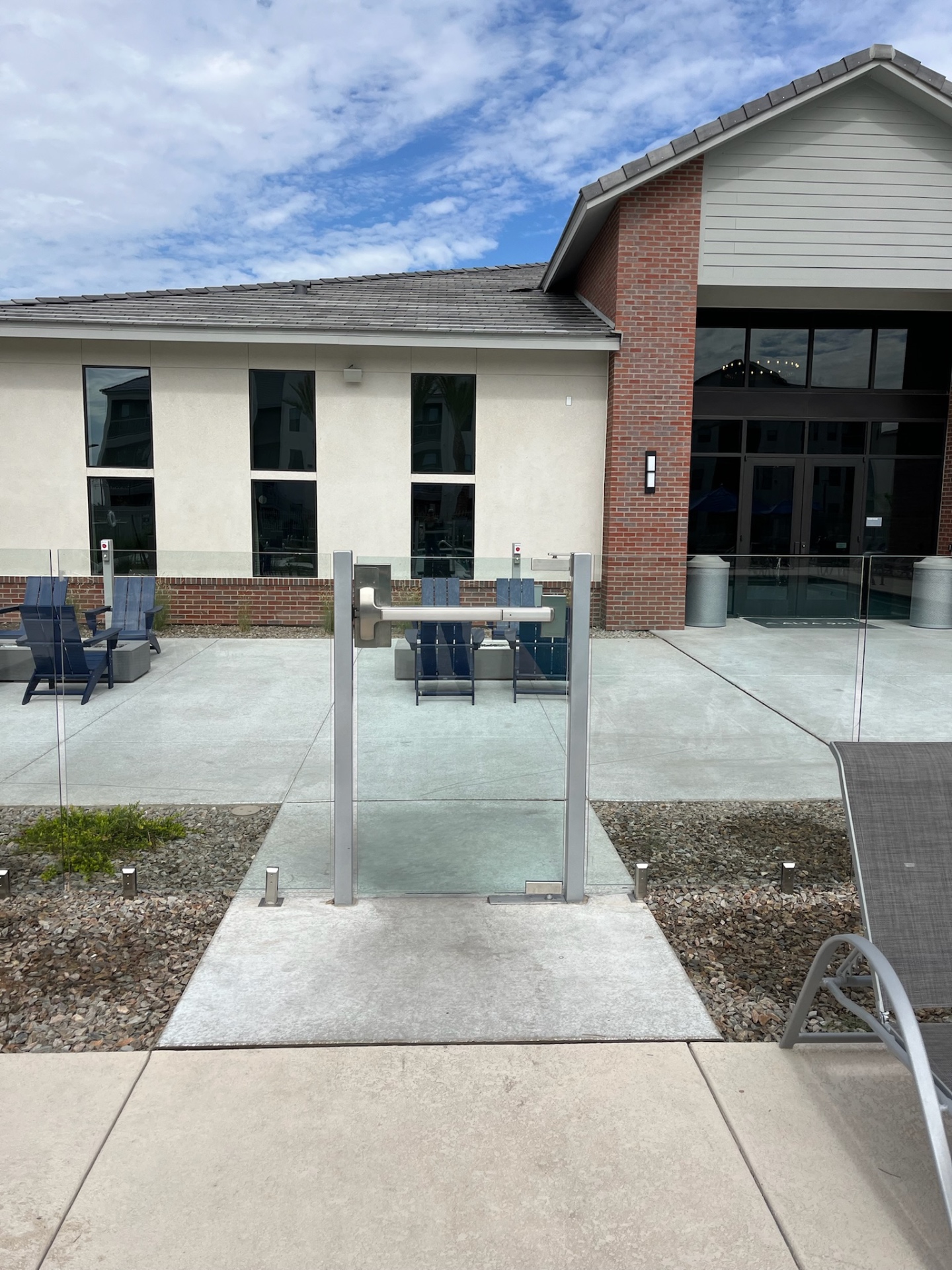 Commercial glass fence entry gate with hydraulic closer and latch hardware at a multifamily amenity area — Arizona commercial glass fencing.