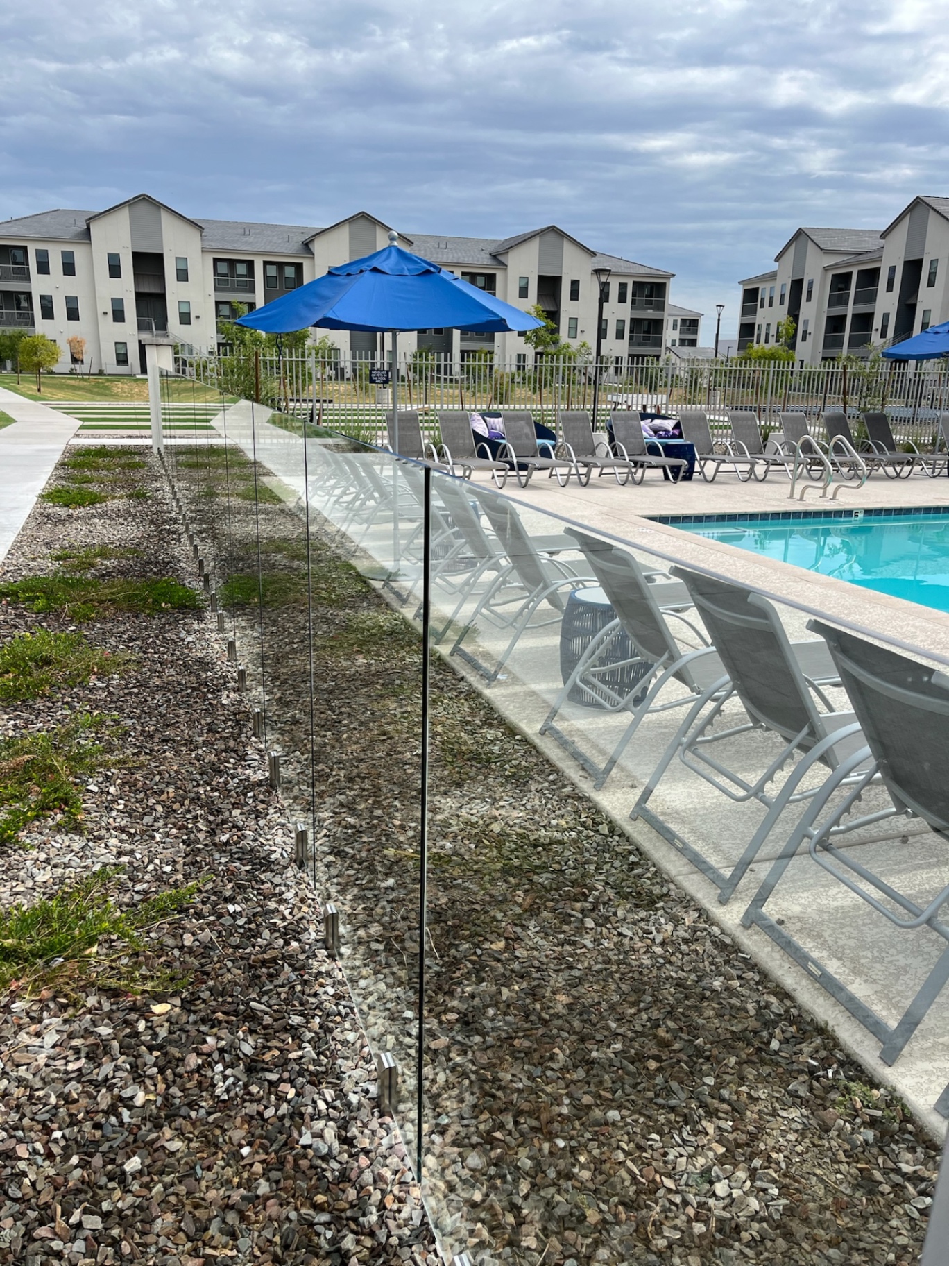 Long run of commercial frameless glass fence panels with stainless spigots along an apartment community pool deck in Phoenix.