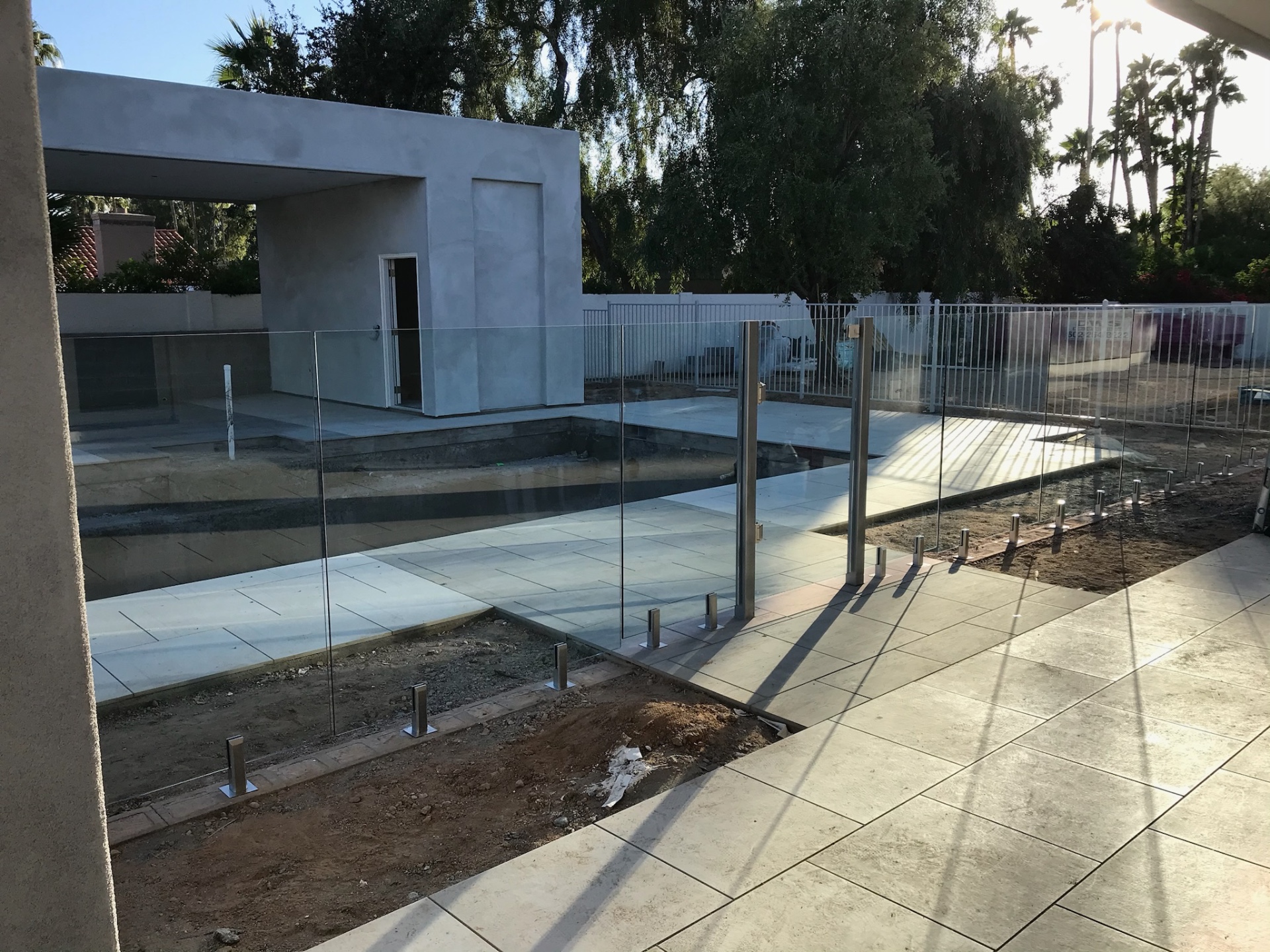 Wide view of glass fence panels enclosing a new pool, spa, and pavilion — glass fencing in Arizona with porcelain paver decking and stainless spigot mounts.