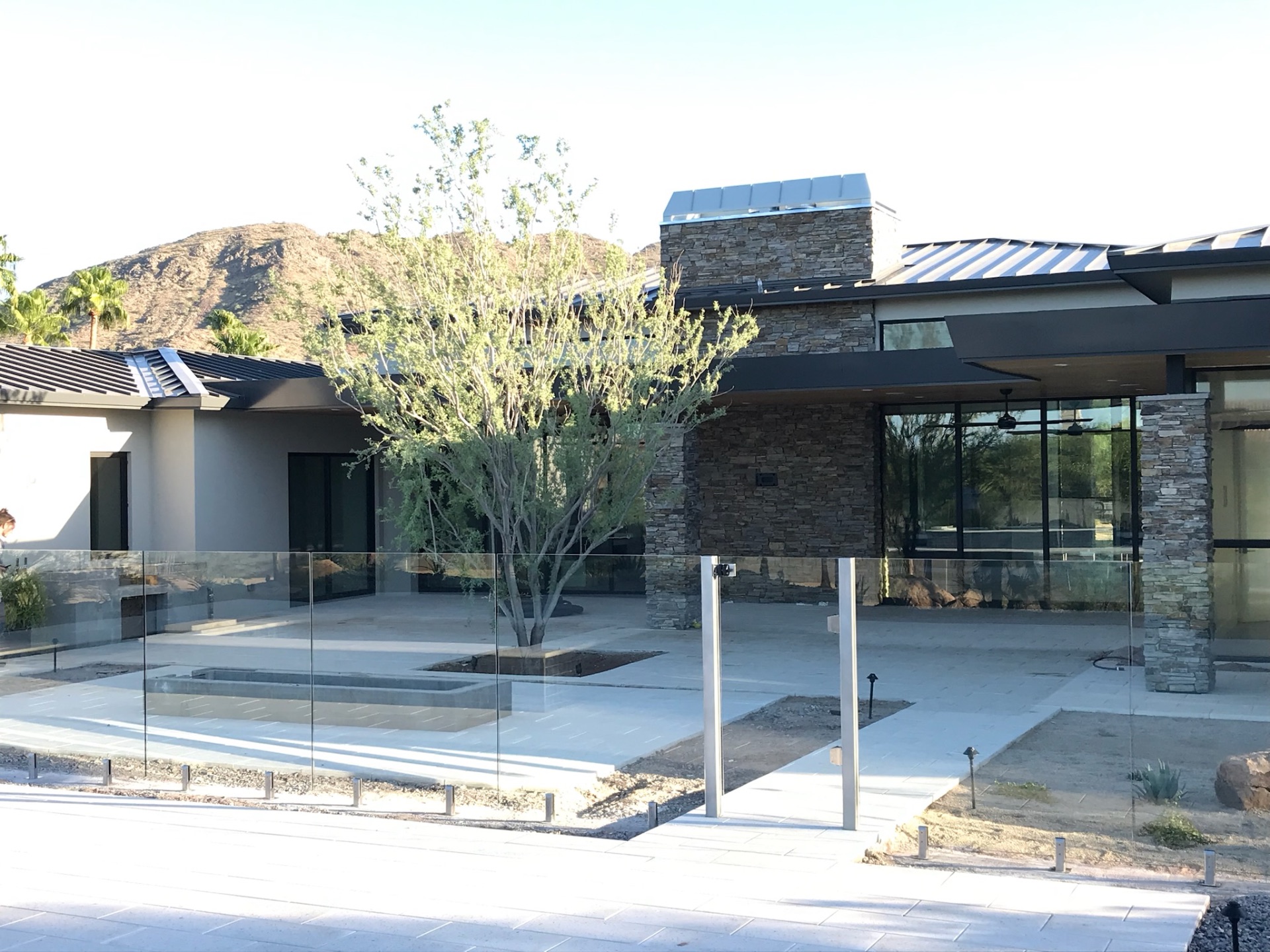 Modern home architecture and covered patio seamlessly integrated with clear frameless glass fence panels around the pool enclosure.