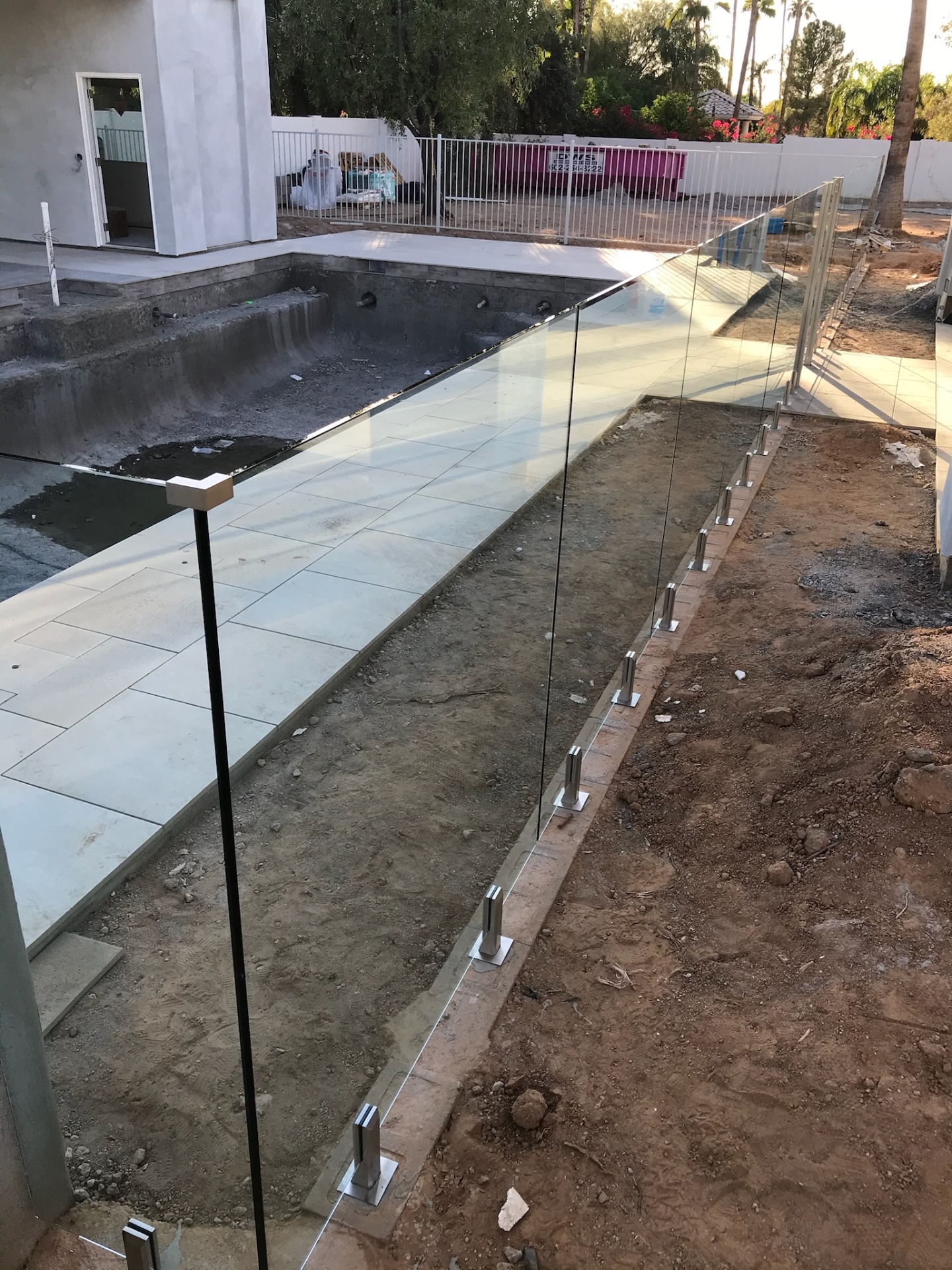 Frameless glass fence following the pool deck edge with stainless spigots anchored into the bond beam, viewed from inside the Arizona glass fencing enclosure.