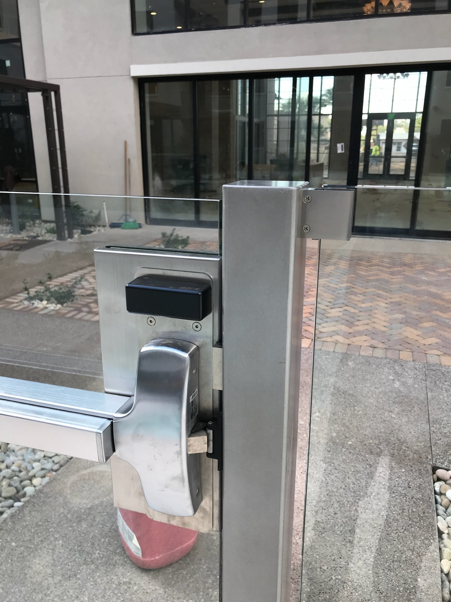 Detail of commercial gate hardware mounted through tempered glass fence panels at a multifamily pool-barrier entrance in Arizona.