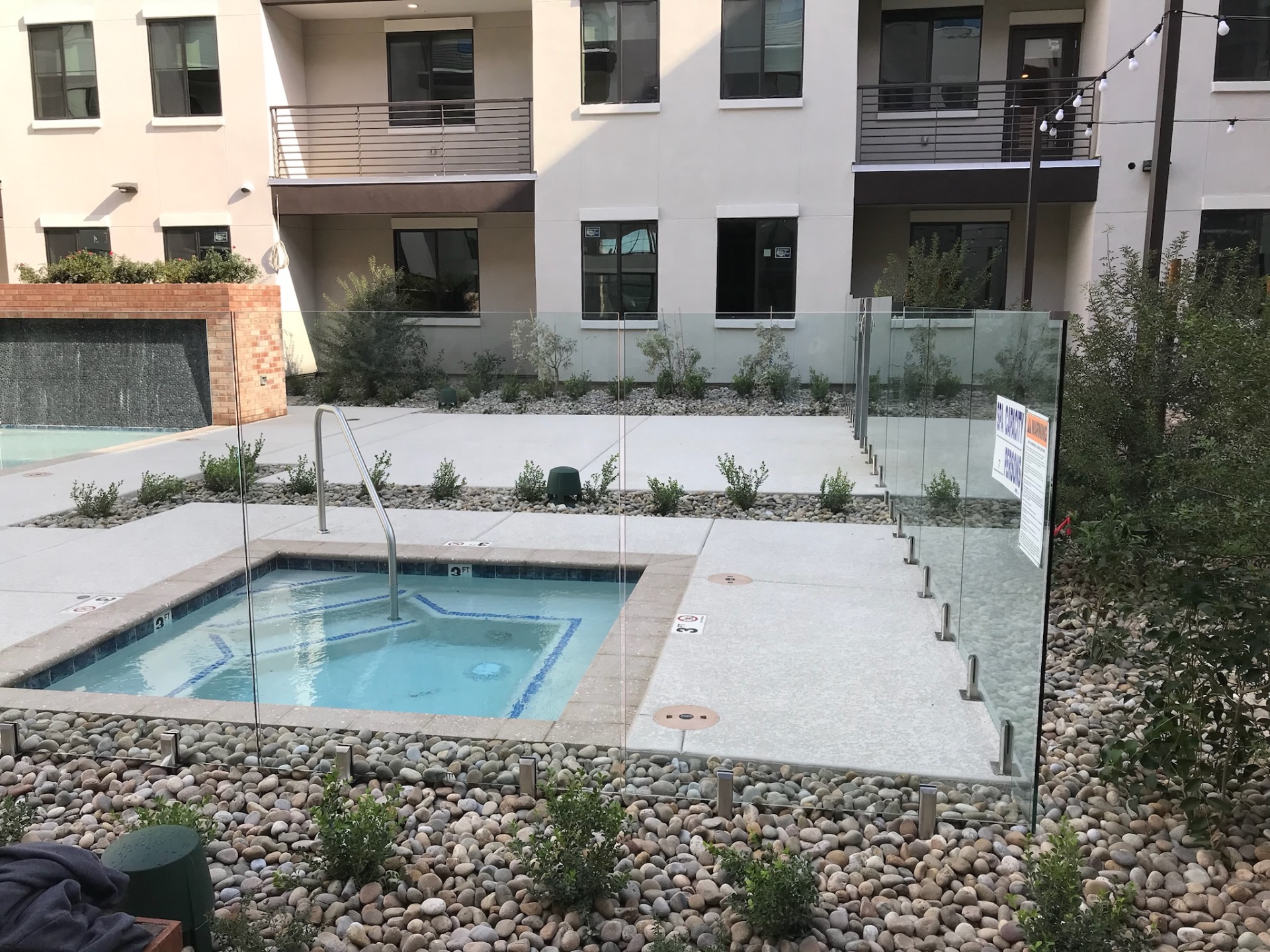 Commercial frameless glass fencing protecting a spa and pool deck at an Arizona apartment community with clear sightlines across the amenity court.