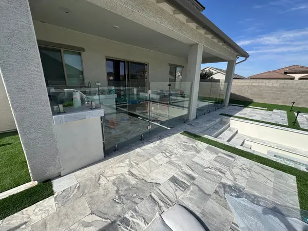 Glass fence panels on porcelain marble-look pavers with stainless spigots — glass fencing in Arizona installed by Sonoran Glass in the Phoenix metro.
