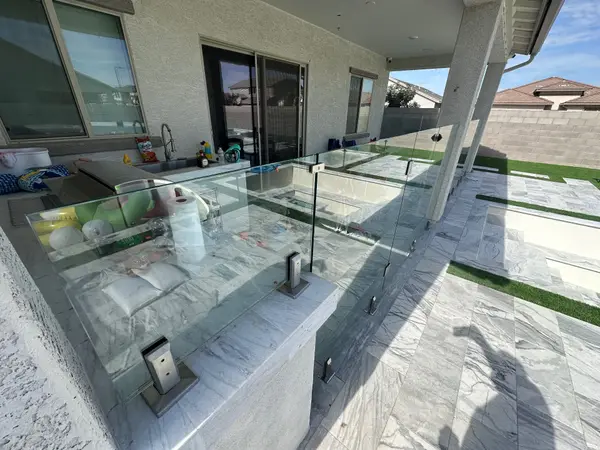 Close-up of tempered glass fence panels and stainless spigot bases anchored into the pool deck on a Phoenix glass fencing install.