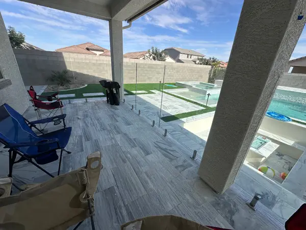 Frameless glass fence framing the pool view from a covered patio — clear sightlines to spa and water feature on an Arizona glass fencing project.